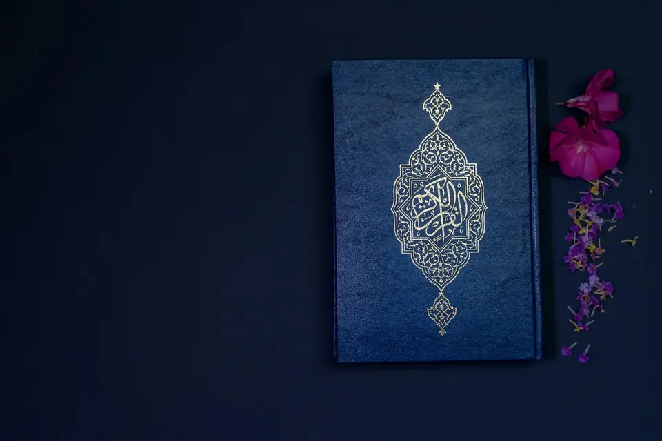 مصحف مغلق بجانب زهور على خلفية داكنة
